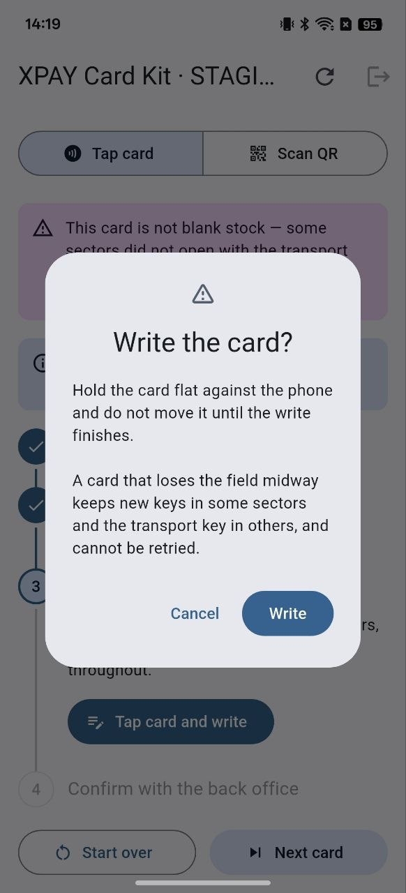 Hộp thoại xác nhận “Write the card?”: “Hold the card flat against the phone and do not move it until the write finishes. A card that loses the field midway keeps new keys in some sectors and the transport key in others, and cannot be retried.” kèm hai nút “Cancel” và “Write”.